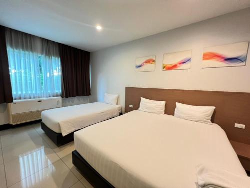 ein Hotelzimmer mit zwei Betten und Gemälden an der Wand in der Unterkunft Crystal Suites Suvarnbhumi Airport in Lat Krabang