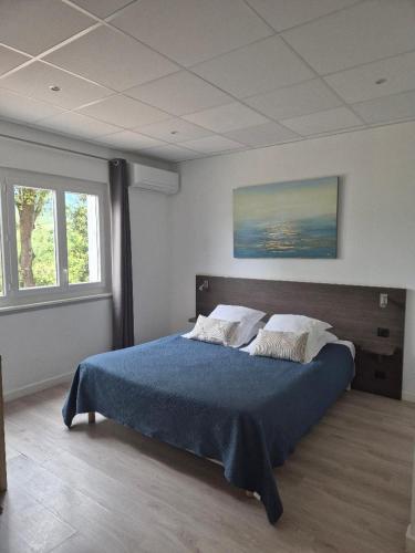 a bedroom with a large bed with a blue blanket at Hôtel Restaurant Les Chasseurs in Marine de Pietracorbara
