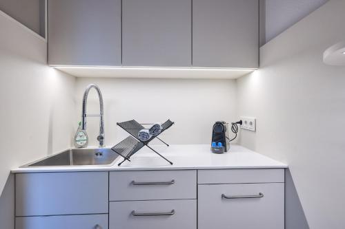 a kitchen with white cabinets and a sink at seeglueck Altstadt Urban in Konstanz