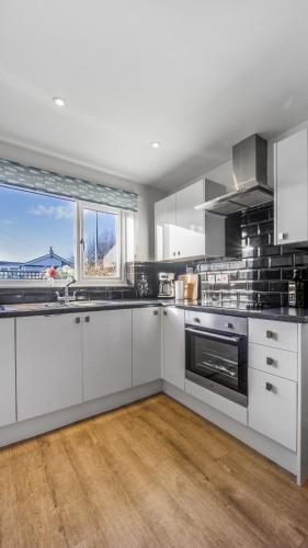 a kitchen with white cabinets and a large window at No 1 Rhosffordd in Moelfre