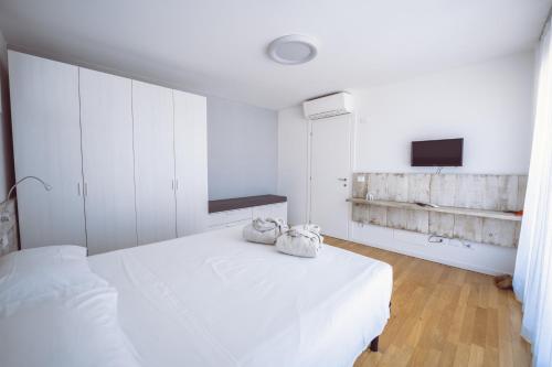 a white bedroom with two towels on a bed at Aurea Attico con Jacuzzi e vista mare Lignano in Lignano Sabbiadoro