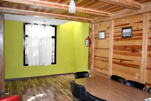 a dining room with a table and a green wall at Cabañas el Chalet in Morelia