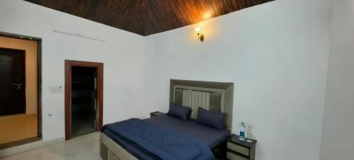 a bedroom with a blue bed in a white wall at Party Place with pool in Ballabgarh