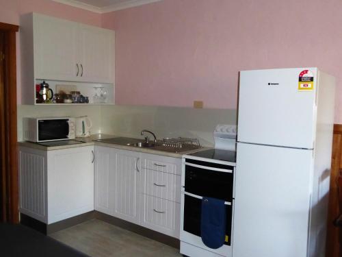 a kitchen with white cabinets and a white refrigerator at Platypus Park Country Retreat in Bridport