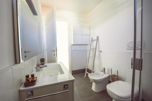 a white bathroom with a sink and a toilet at Aurea Attico con Jacuzzi e vista mare Lignano in Lignano Sabbiadoro