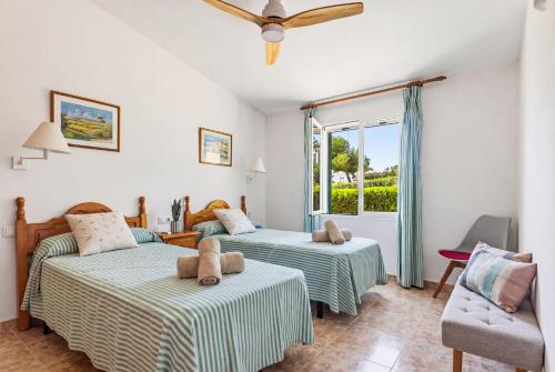 a bedroom with two beds and a chair and a window at Villa Ca Mestre Rafel by Escape Home in Santo Tomás