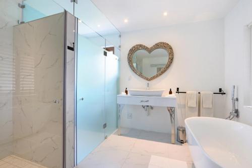 een badkamer met een bad, een wastafel en een spiegel bij Apricot Gardens Guesthouse in Gordonsbaai