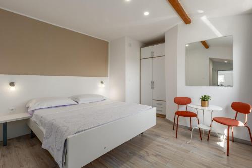 a bedroom with a white bed and two red chairs at House Prenc in Pazin