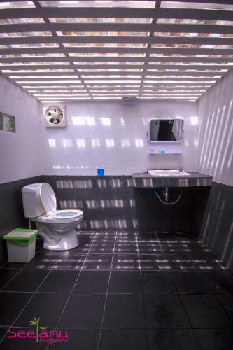 a bathroom with a toilet and a tv on the wall at Seetanu Bungalows in Srithanu