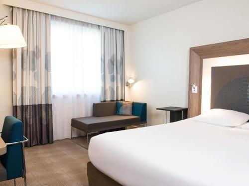 a hotel room with a bed and a chair at Novotel Brussels City Centre in Brussels