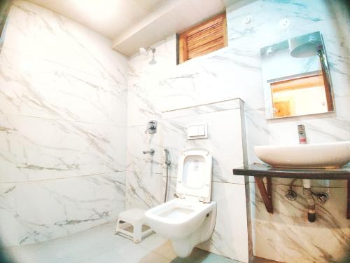 a white bathroom with a sink and a toilet at Hans Cottage in Shimla