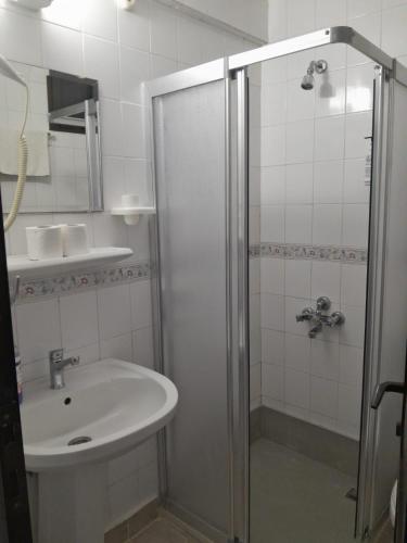 a white bathroom with a shower and a sink at Çidihan HOTEL in Kuşadası