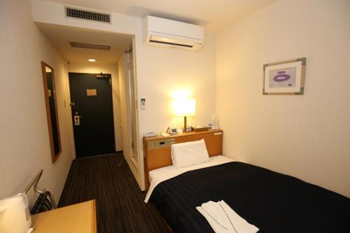 a small room with a bed and a lamp at Kyoto Plaza Hotel in Kyoto