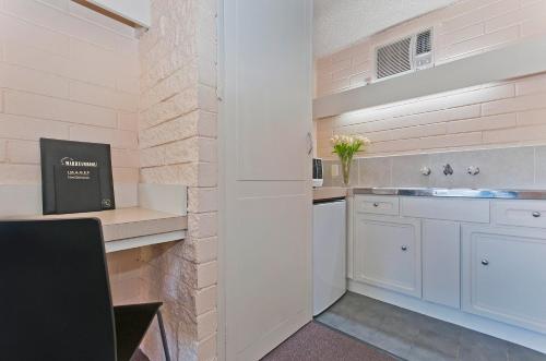 uma cozinha com armários brancos e um lavatório em Mahogany Motel Warrnambool em Warrnambool