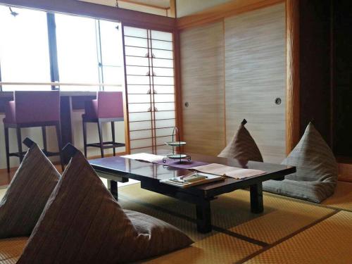 a living room with a coffee table and pillows at Hanano Koyado Jyu-bei in Toba