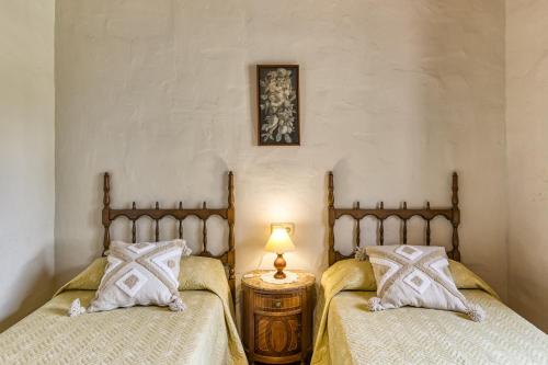 two twin beds in a bedroom with a lamp on a table at Mas Pareta - La Morera in Fonolleras