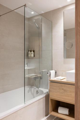 a bathroom with a shower and a tub and a sink at Apartaments SB Corona Tortosa in Tortosa