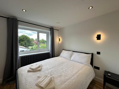 a bedroom with a bed with white sheets and a window at Roundhay Residences in Moortown