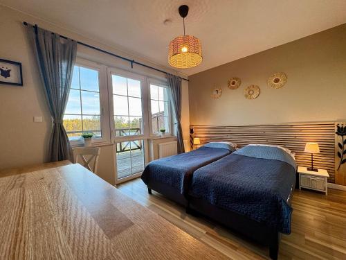 a bedroom with a bed and a large window at Wyspa Kaszubska dom wypoczynkowy z sauną i balią in Lipnica