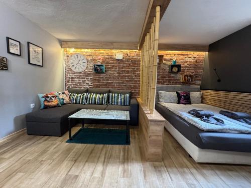 a living room with a couch and a brick wall at City Garden Studio in Plovdiv