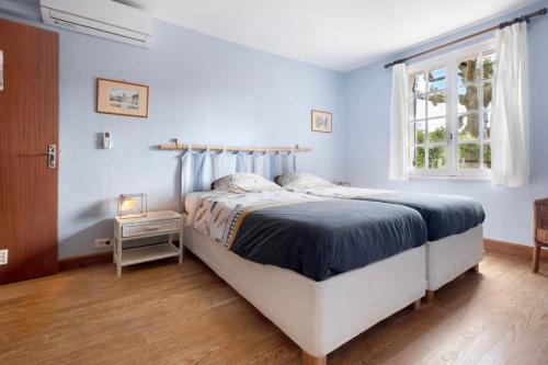 a bedroom with a bed with blue walls and a window at Gite La Forge in Le Buisson de Cadouin