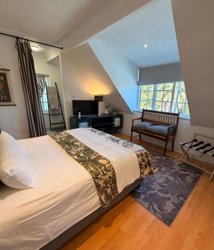 a bedroom with a large bed and a chair at Almond Cottage Bed & Breakfast in Somerset West