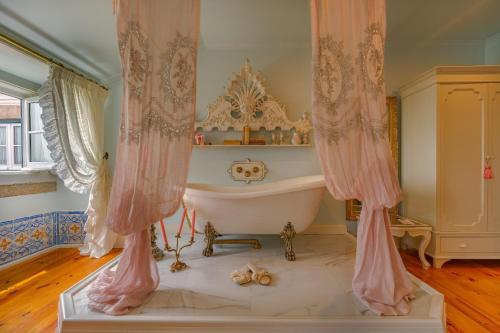 a bathroom with a tub in a room with curtains at Palácio das Especiarias in Lisbon