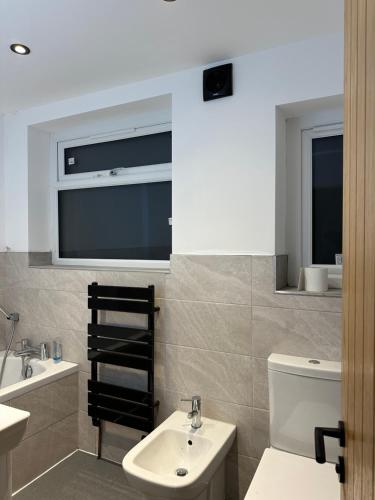 a bathroom with a sink and a toilet and a window at Roundhay Residences in Moortown