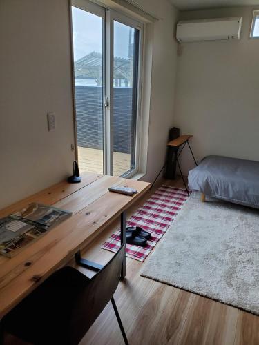 a bedroom with a wooden desk and a large window at 鉾田の家 in Hokota