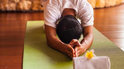 a man is doing yoga on a green mat at Qunci Villas Resort in Senggigi 