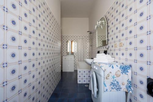 a bathroom with blue and white tiled walls and a sink at oasi corallo in Diano Marina