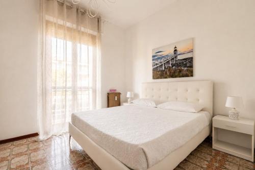 a white bedroom with a large bed and a window at oasi corallo in Diano Marina