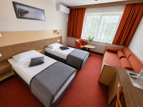 a hotel room with two beds and a couch at Info Hotel in Palanga