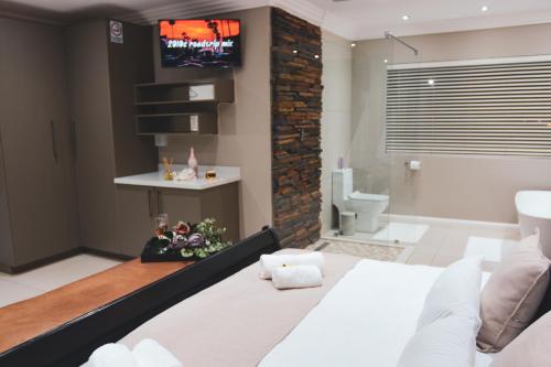 a bedroom with a bed and a tv on the wall at Palmera Guest House in Krugersdorp