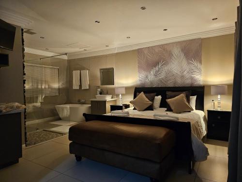 a bedroom with a bed and a bathroom with a tub at Palmera Guest House in Krugersdorp