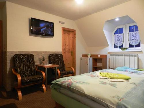 a bedroom with a bed and two chairs and a tv at Penzión Soňa in Ždiar