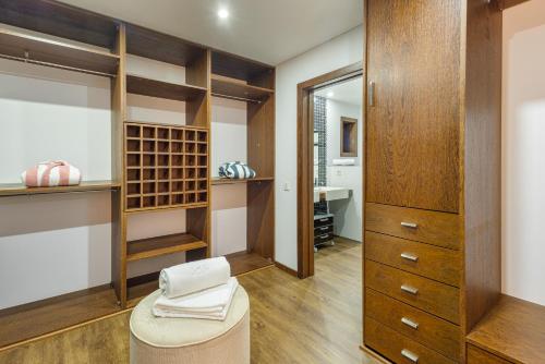 a walk in closet with wooden cabinets and a stool at Luxury by ON Apartments in Porto