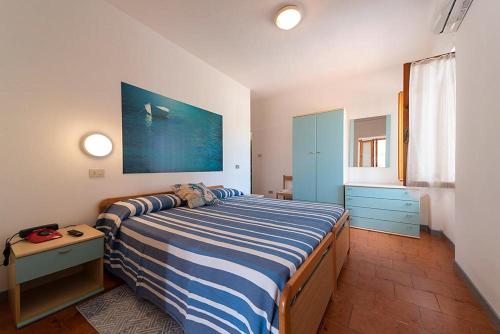 a bedroom with a bed with a blue and white striped blanket at B&B Hotel Il Veliero - la vela del veliero in SantʼAndrea