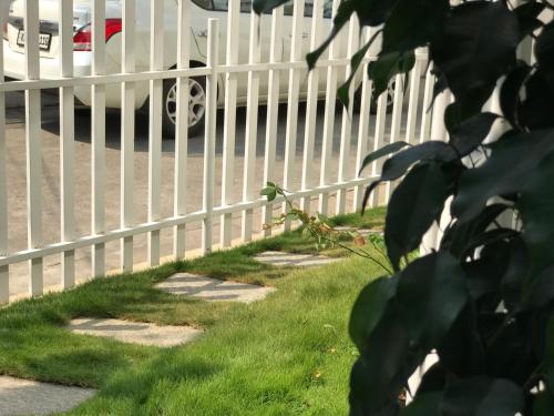 a white fence next to a road with a car at Daffodils Spice Court in Cochin