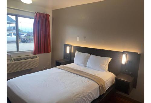 a bedroom with a bed with white sheets and a window at Motel 6 Gulfport, MS Airport in Gulfport