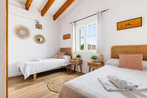 a bedroom with two beds and a window at Villa Rouss by Escape Home in Cala en Porter