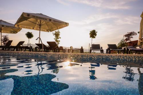 a swimming pool with chairs and an umbrella at Hotel Relax & Resort Sovata in Sovata