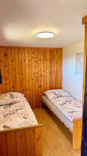 two beds in a room with wooden walls at Chata pod Černou horou in Rudník