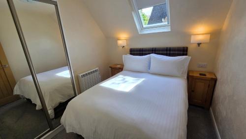a bedroom with a large white bed and a mirror at Bunroy Park in Fort William