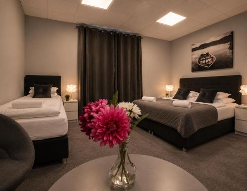 a bedroom with two beds and a vase with flowers on a table at Tjarna Hotel in Keflavík