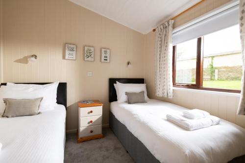 two twin beds in a room with a window at L23 Cormorant in Truro