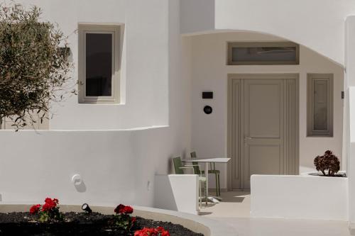 a room with white walls and a door and flowers at Filomare Oia Suites in Oia
