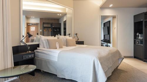 a bedroom with a large white bed and a mirror at Solo Sokos Hotel Paviljonki in Jyväskylä