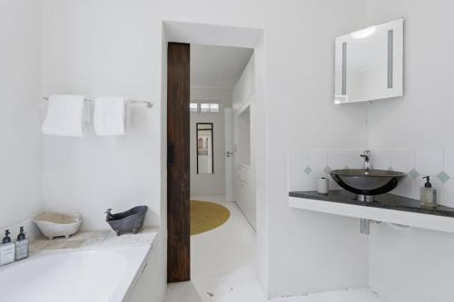 a white bathroom with a sink and a mirror at Modern Cozy Upper Wynberg Cottage in Cape Town
