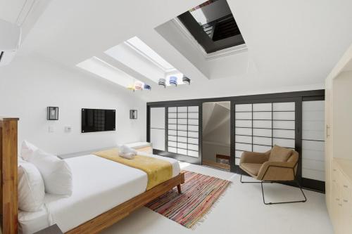 a bedroom with a bed and a chair at Modern Cozy Upper Wynberg Cottage in Cape Town